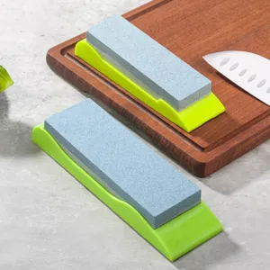 Vue détaillée de la pierre à aiguiser de cuisine double face avec base verte sur planche.