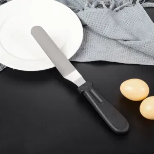 Spatola per dolci angolata in acciaio inossidabile con manico nero per dettaglio cottura.