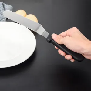 Vista dettagliata di una spatola per glassa in acciaio inossidabile con manico nero da cucina.