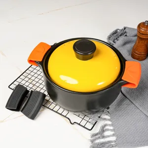 Detailed view of the casserole pot with vibrant yellow lid and orange silicone handle covers.