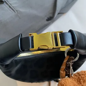 Λεπτομέρεια μαύρης τσάντας ώμου με λεοπάρ σχέδιο, χρυσή αγκράφα και χνουδωτό γούρι.
