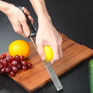 Stainless steel lemon zester and cheese grater for kitchen use, detailed view of the sharp blade.