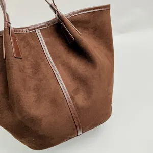 Λεπτομέρεια καφέ σουέτ bucket bag, μεγάλη κομψή γυναικεία τσάντα ώμου minimal chic.