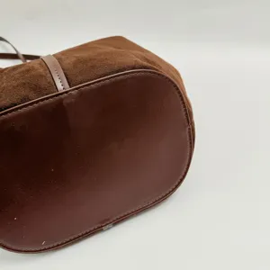 Λεπτομέρεια πάτου τσάντας από καφέ σουέτ, που δείχνει υφή δέρματος και ραφές.