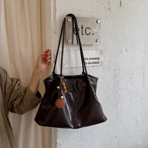 Retro dark brown tote bag detail showing soft leather texture and chic wooden bead pendant.