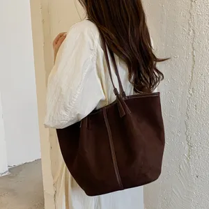 Λεπτομερης οψη ρετρο σκουροκαφε τσαντας ωμου που φοριεται μπροστι σε μινιμαλιστικο τοιχο.