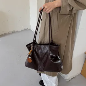 Detail shot of a retro brown leather tote bag with shoulder straps and cute wooden bead charms.
