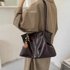 Brown leather tote bag, soft slouchy shoulder bag with bead charm, chic casual accessory.