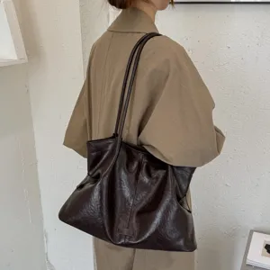 Detailed shot of dark brown crinkled leather tote bag, soft underarm shoulder bag for women.