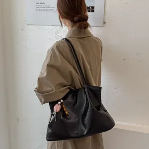 Detail shot of a stylish black slouchy leather shoulder tote bag worn by a model on back.