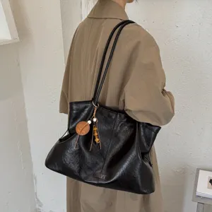 Detail view of the vintage black soft leather slouchy shoulder tote bag with wooden charm.
