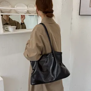 Detailed view of a black retro shoulder tote bag worn by a woman, showing style and texture.