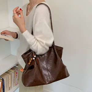 Detailed view of dark brown PU leather tote bag, casual large capacity shoulder bag for daily use.