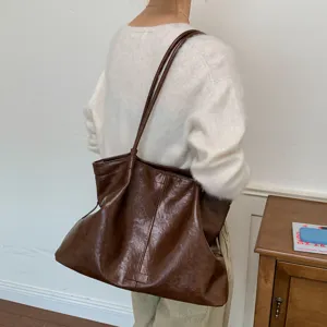 Detail view of a retro brown leather tote bag worn on shoulder, elegant daily commuting style.