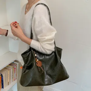 Detailed view of women's vintage green leather shoulder tote bag in daily lifestyle scene.