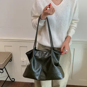 Detailed shot of dark green leather tote bag, soft slouchy texture for daily casual wear.