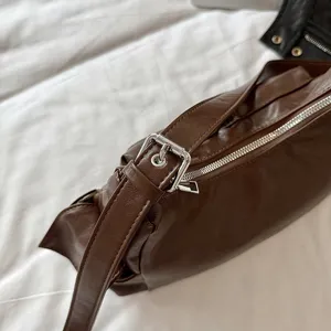 Brown leather shoulder bag detail shot, stylish multi-pocket commuter crossbody bag.