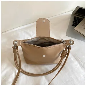 Detailed view of beige women crossbody shoulder bag interior zipper and magnetic flap closure.