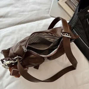 Close-up detail view of brown PU leather shoulder crossbody bag with striped lining and pockets.