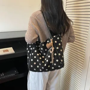 Detail view of a chic polka dot tote bag with cute heart charm and large capacity design.