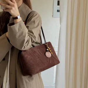 Brown suede shoulder bag for women, retro underarm tote bag with wooden charm detail.