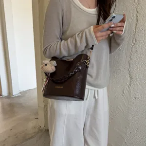 Sac seau marron rétro avec poignée tressée et charmant pendentif, sac bandoulière élégant.