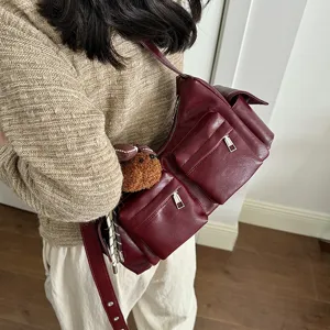 Detailed view of women's multi-pocket shoulder bag with cute bear pendant and zippers.