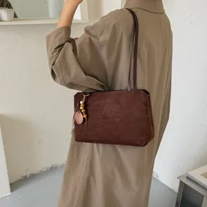 Brown suede underarm shoulder bag with beaded charm, stylish vintage commuting tote.