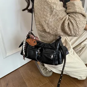 Detailed view of black PU leather shoulder bag featuring multi pockets and cute charms.