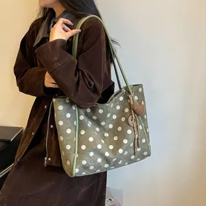 Detail view of large capacity green polka dot canvas shoulder tote bag with cute heart charm.