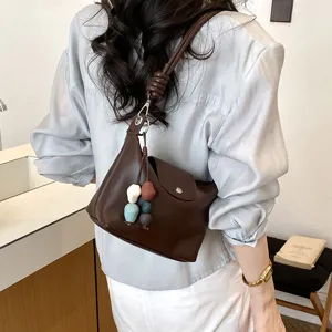 Detailed view of the dark brown shoulder bag with knotted handle and beaded charm.