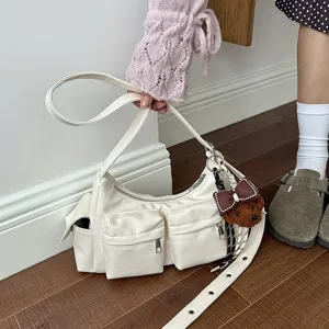 Detail view of white PU leather shoulder bag with multiple front pockets and cute bear charm.