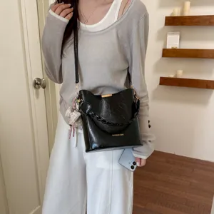 Sac seau noir chic pour femme, sac à bandoulière rétro avec poignée tressée et pendentif.