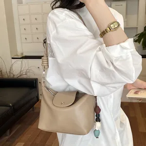 Detail shot of a vintage khaki shoulder bag worn by model, showing soft leather and knot strap.