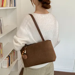 Brown suede shoulder bag detail view, vintage underarm handbag with wooden bead pendant.