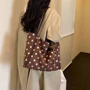 Detailed shot of a stylish brown polka dot tote bag with shoulder straps and cute charm.