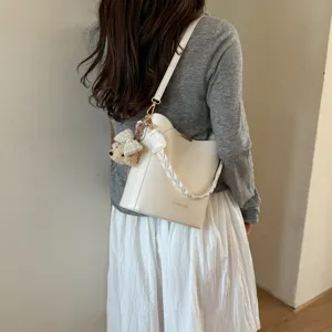 Vue détaillée du sac seau blanc tendance avec poignée tressée et un joli pendentif ours.
