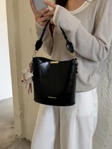 Sac seau en cuir verni noir avec poignée tressée et charmant pendentif pour mode féminine.