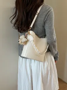 Élégant sac seau blanc avec poignée tressée et charmant pendentif pour un usage quotidien.