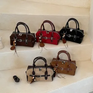 Nahaufnahme retro Boston Handtaschen in verschiedenen Farben mit Wildlederoptik und Anhängern.