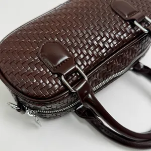 Nahaufnahme einer dunkelbraunen geflochtenen Ledertasche mit feiner Textur und Hardware.