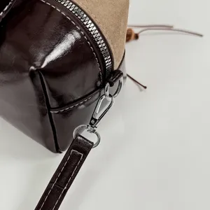 Nahaufnahme der braunen Patchwork Boston Tasche mit Lackleder und glänzenden Metallteilen.
