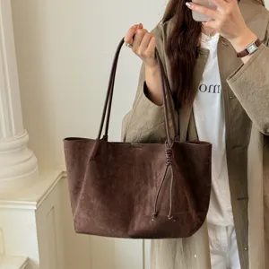 Brown suede tote bag detail, slouchy shoulder bag design with strap knots for daily commuting.