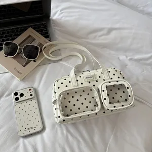 Detailed view of white polka dot bowling handbag with transparent front pockets and straps.