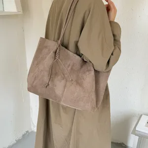 Detail view of the brown suede shoulder tote bag, showcasing textured fabric and knotted strap.