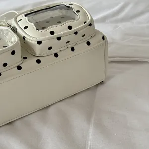 Detailed closeup shot of white polka dot shoulder bag, synthetic leather texture detail view.