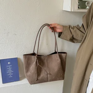 Brown suede tote bag detail, minimalist retro shoulder bag design with slim straps and knot.