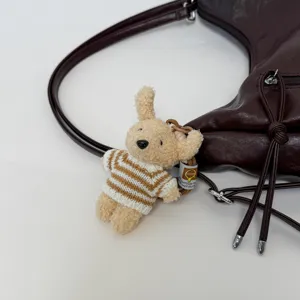 Detailed view of women casual shoulder bag decorated with cute knitted bear plush pendant.