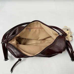 Detail view of large capacity dark brown leather tote shoulder bag interior structure and cute bear charm.