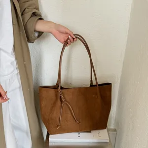Brown suede tote bag detail view showing soft texture, stylish knot handle, and spacious design.